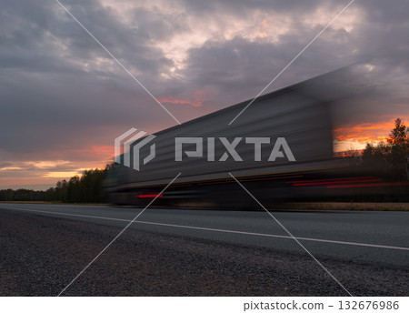 Large truck moving quickly along a highway during a vibrant sunset with dramatic clouds in the background Large truck moving quickly along a highway during a vibrant sunset with dramatic clouds in the background 132676986