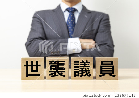 A businessman with his arms crossed and a block that reads "Hereditary politician" A businessman with his arms crossed and a block that reads "Hereditary politician" 132677115