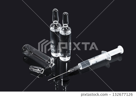 Ampoules with transparent vaccine and syringe on dark background 132677126