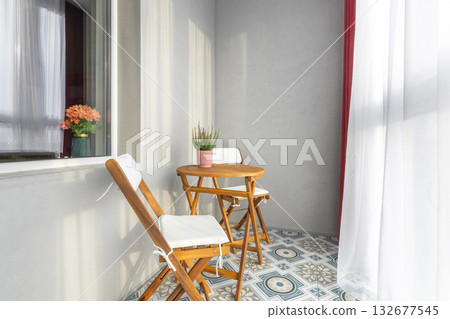 Sunny Balcony with Wooden Furniture and Patterned Floor 132677545