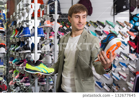 Smiling young man choosing sneakers in sports store 132677645