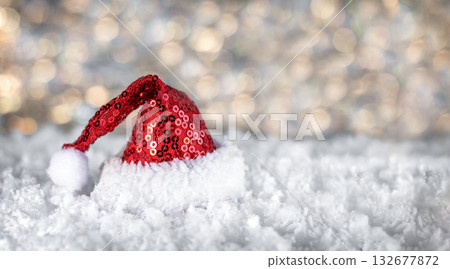 Red Santa hat in snowy scene with sparkle and festive mood for Christmas holiday stock photo 132677872