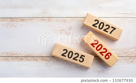 Three Wooden Blocks with 2025, 2026, and 2027 Arranged Diagonally on White Wood Background 132677930