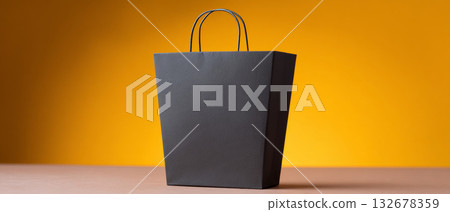 A black paper bag with handles on a yellow background 132678359