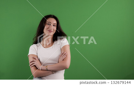 Confident young woman smiling with crossed arms on green screen background 132679144