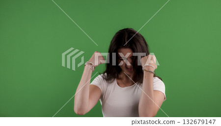 Young woman showing frustration raising fists on green screen background Young woman showing frustration raising fists on green screen background 132679147