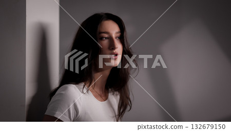 Fashion model posing near a wall with interesting shadows Fashion model posing near a wall with interesting shadows 132679150
