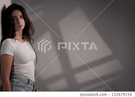 Fashion model posing near wall with window shadows Fashion model posing near wall with window shadows 132679158