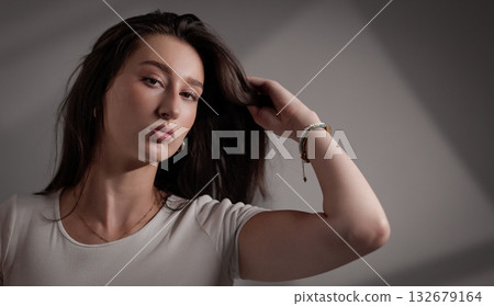 Fashion model touching her hair in studio with gray background 132679164