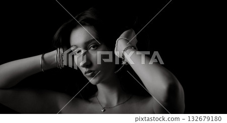 Fashion model holding her hair with bracelets on black background 132679180