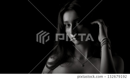 Fashion model posing in low key lighting touching her hair Fashion model posing in low key lighting touching her hair 132679192
