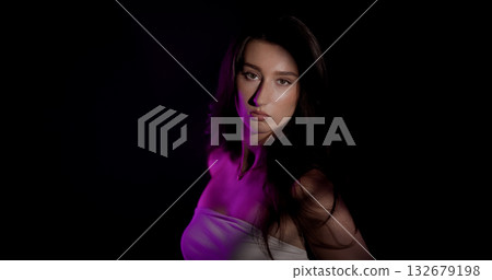 Fashion model posing in studio with purple light on black background 132679198