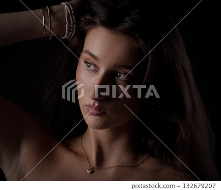 Fashion model posing with hand in hair and gold necklace Fashion model posing with hand in hair and gold necklace 132679207