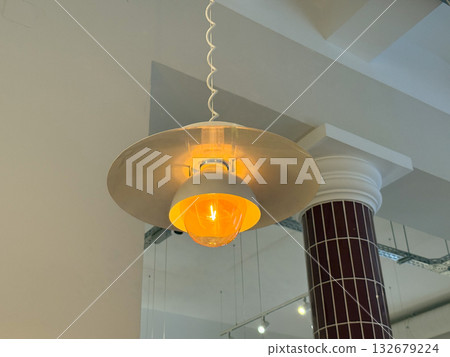 Modern pendant lamp glowing in cafe interior. Warm lighting, architectural design and cozy urban ambiance with industrial aesthetic. Modern pendant lamp glowing in cafe interior. Warm lighting, architectural design and cozy urban ambiance with industrial aesthetic. 132679224