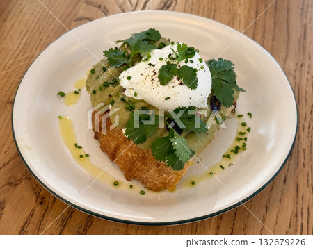 Close-up avocado toast with poached egg and herbs on plate. Healthy breakfast, modern cuisine and fresh culinary aesthetics with natural ingredients 132679226