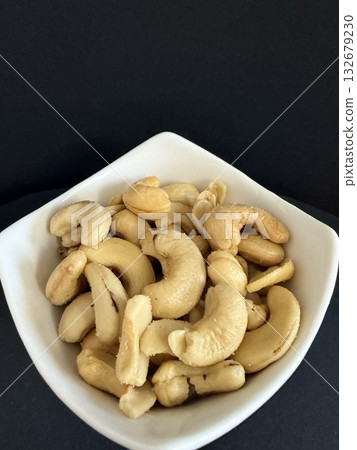 Close-up of dried cashews in a white bowl. Healthy, natural food. Close-up of dried cashews in a white bowl. Healthy, natural food. 132679230
