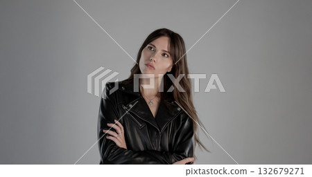 Fashion model wearing black leather jacket is posing with arms crossed 132679271