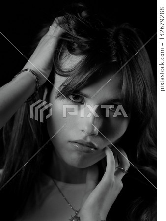 Fashion model touching her hair and face posing in black and white Fashion model touching her hair and face posing in black and white 132679288