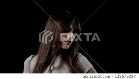 Fashion model with long brown hair wearing white t shirt and necklace looking down on black background Fashion model with long brown hair wearing white t shirt and necklace looking down on black background 132679297