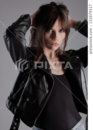 Fashion model wearing black leather jacket holding her hair Fashion model wearing black leather jacket holding her hair 132679317