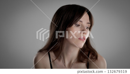 Fashion model posing with long brown hair and black bra on gray background Fashion model posing with long brown hair and black bra on gray background 132679319