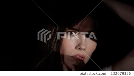 Fashion model posing in the shadows with hand on her face Fashion model posing in the shadows with hand on her face 132679336