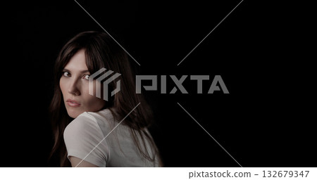 Fashion model looking over shoulder on black background Fashion model looking over shoulder on black background 132679347