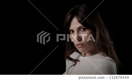 Fashion model posing with serious expression on black background Fashion model posing with serious expression on black background 132679349