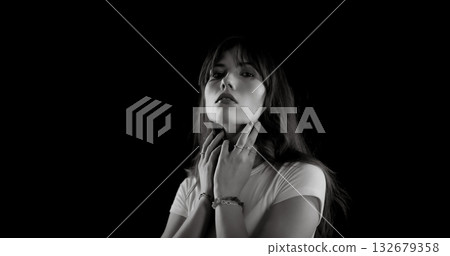 Fashion model gently touching her neck with both hands in black and white portrait Fashion model gently touching her neck with both hands in black and white portrait 132679358