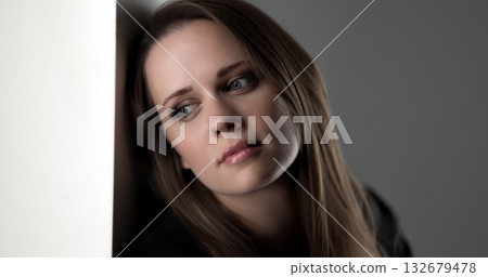 Sad woman leaning against white wall looking away 132679478