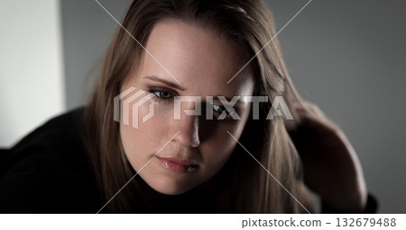 Young woman playing with her hair looking down with a pensive expression 132679488