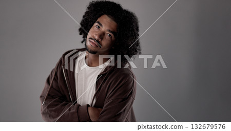 Young african-american man with curly hair and crossed arms posing in studio 132679576