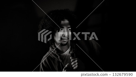 Young african-american man with curly hair looking away in dark room with shadows on face 132679590