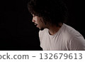Young african-american man with curly hair looking away and talking on black background 132679613