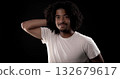 Young african-american man with curly hair touching his head and smiling on black background 132679617