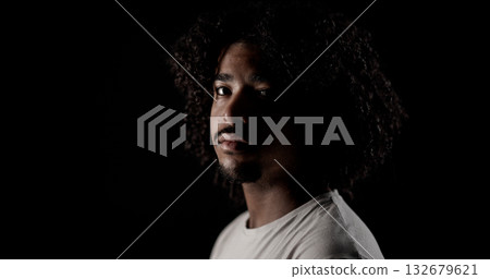 Young african-american man with curly hair posing in studio with black background Young african-american man with curly hair posing in studio with black background 132679621
