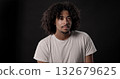Young african-american man with curly hair posing on dark background 132679625