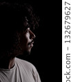 Young african-american man with curly hair looking hopeful in profile on black background 132679627