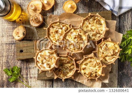 Rustic mushroom tartlets on wooden cutting board perfect for appetizers. Top view flat lay background. Rustic mushroom tartlets on wooden cutting board perfect for appetizers. Top view flat lay background. 132680641
