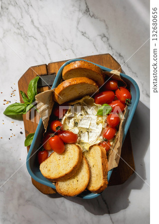 Fresh caprese appetizer with feta, tomatoes, and basil on rustic marble background. 132680656
