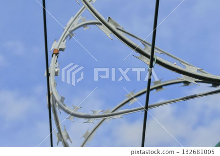 Razor barbed wire on a high security building. Razor wire and heavy-proof wire fencing. The concept of prisons, military facilities, and nuclear power plants. 132681005