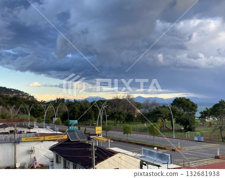 View from the roof of the house to the roofs of houses to the sea, mountains and park, thick low clouds View from the roof of the house to the roofs of houses to the sea, mountains and park, thick low clouds 132681938