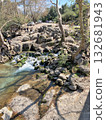The stream of water flows through large stones and forms a small waterfall  132681943