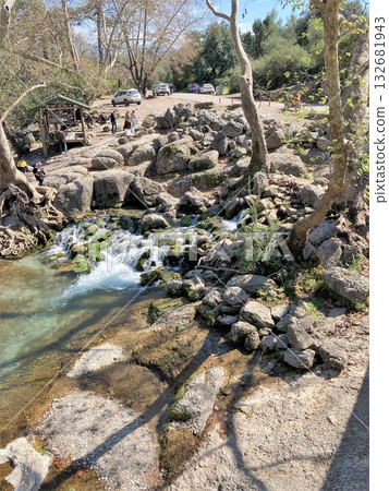 The stream of water flows through large stones and forms a small waterfall The stream of water flows through large stones and forms a small waterfall 132681943