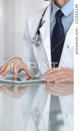 Doctor using digital tablet, consulting with patient, working in healthcare office, telemedicine and medical technology concept. Medicine and health care 132682148