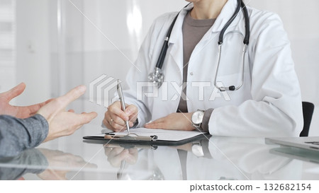 Doctor consulting patient, physician writing medical notes during healthcare examination in modern clinic office. Medicine and health care Doctor consulting patient, physician writing medical notes during healthcare examination in modern clinic office. Medicine and health care 132682154