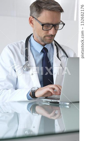Doctor working on laptop, researching patient data, medical professional analyzing healthcare information in office. Medicine and health care 132682176