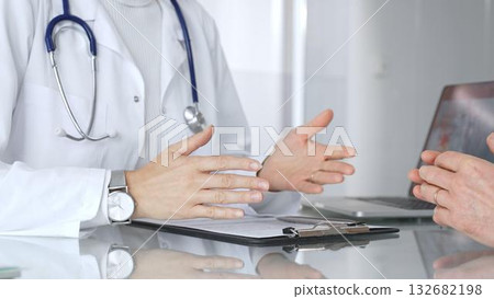Doctor discussing medical information with patient during consultation, showing healthcare advice and diagnostic data on laptop. Medicine, healthcare and science concept 132682198