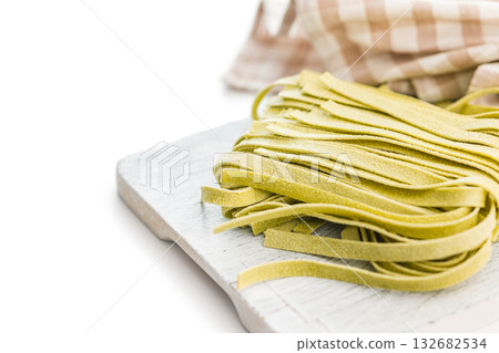 Green tagliatelle pasta on cutting board isolated on white background. 132682534