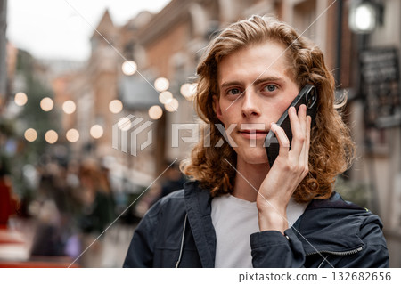 Young man talks on phone in a lively urban street filled with lights Young man talks on phone in a lively urban street filled with lights 132682656